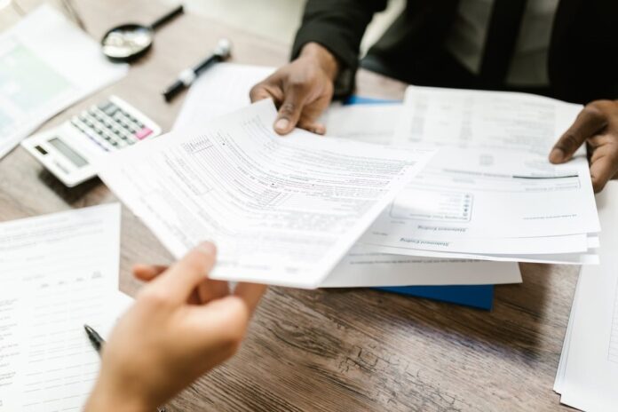 A person handing an insurance claim form to an insurance agent